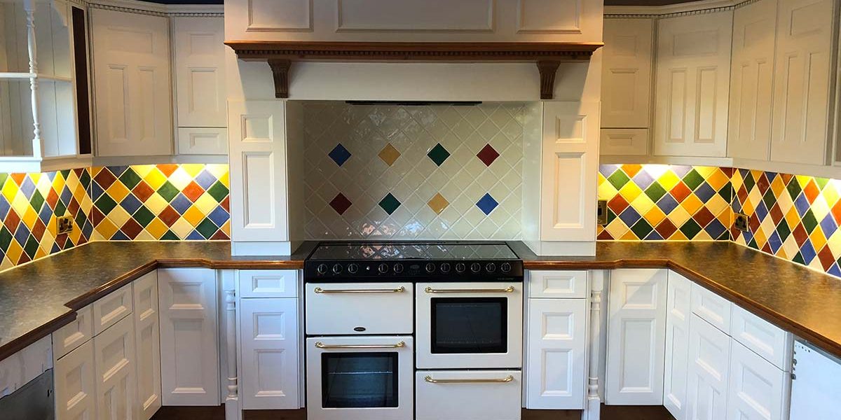 white kitchen showcasing oven with vibrant tiles