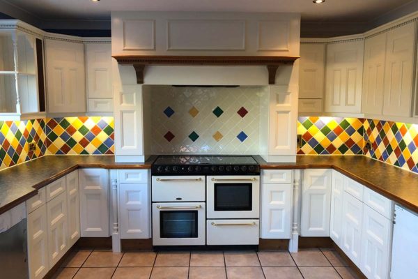 white kitchen showcasing oven with vibrant tiles