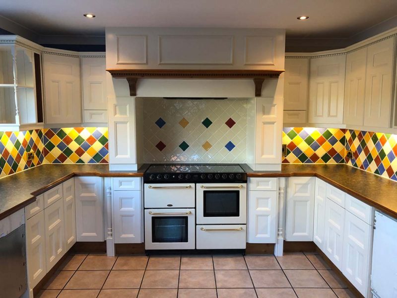 white kitchen showcasing oven with vibrant tiles